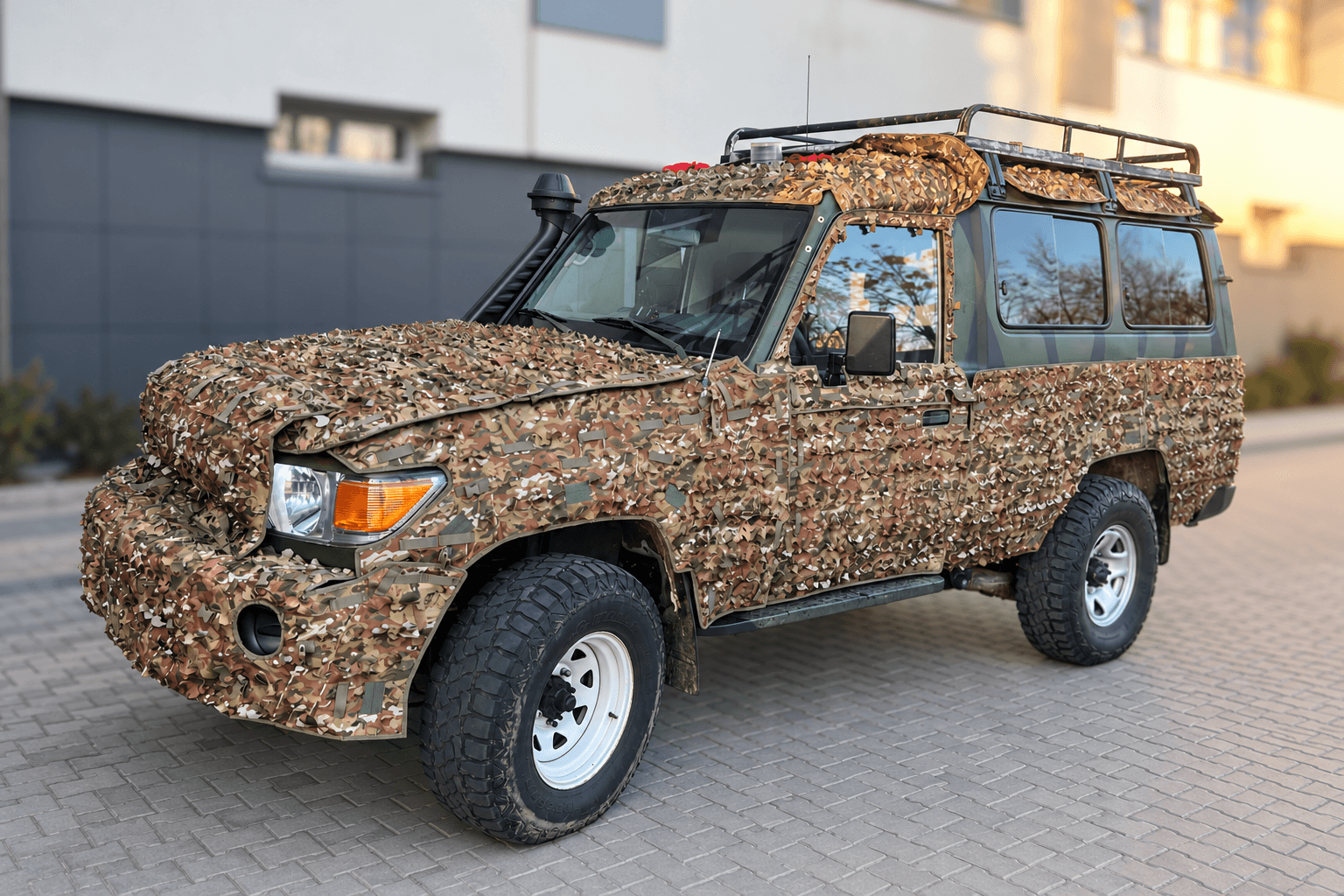 Toyota Land Cruiser (J78) із маскувальним покриттям біля будівлі